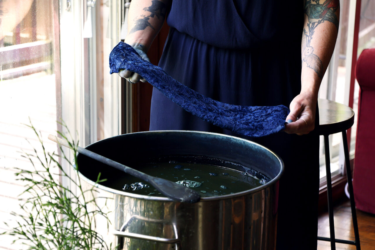 Tissu bleu devant un chaudron de teinture indigo